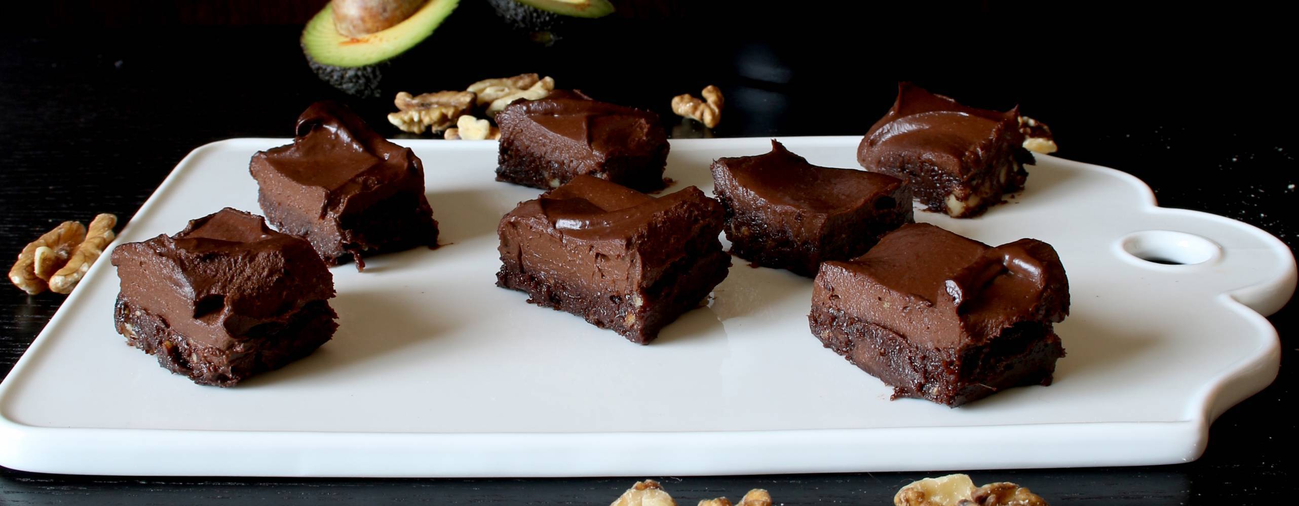 Raw brownie i bitar på en vit skärbräda.