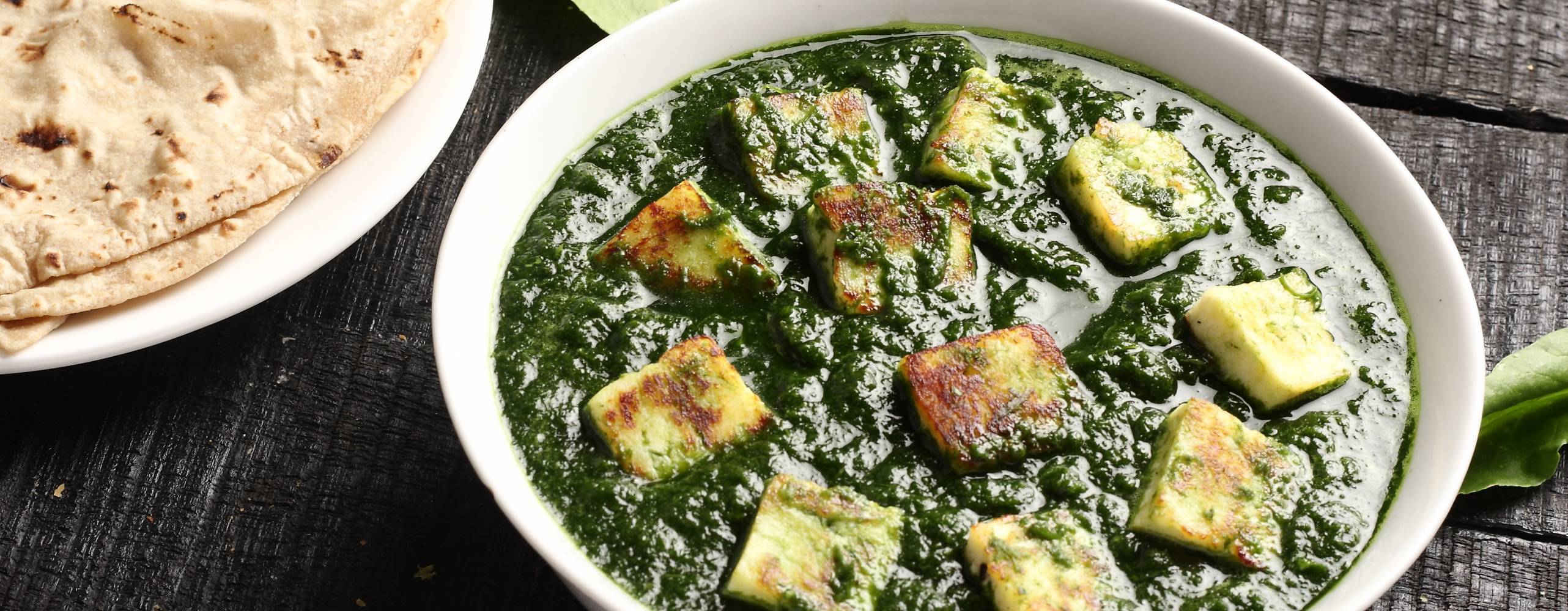 Palak paneer och naan bröd på ett mörkt bord