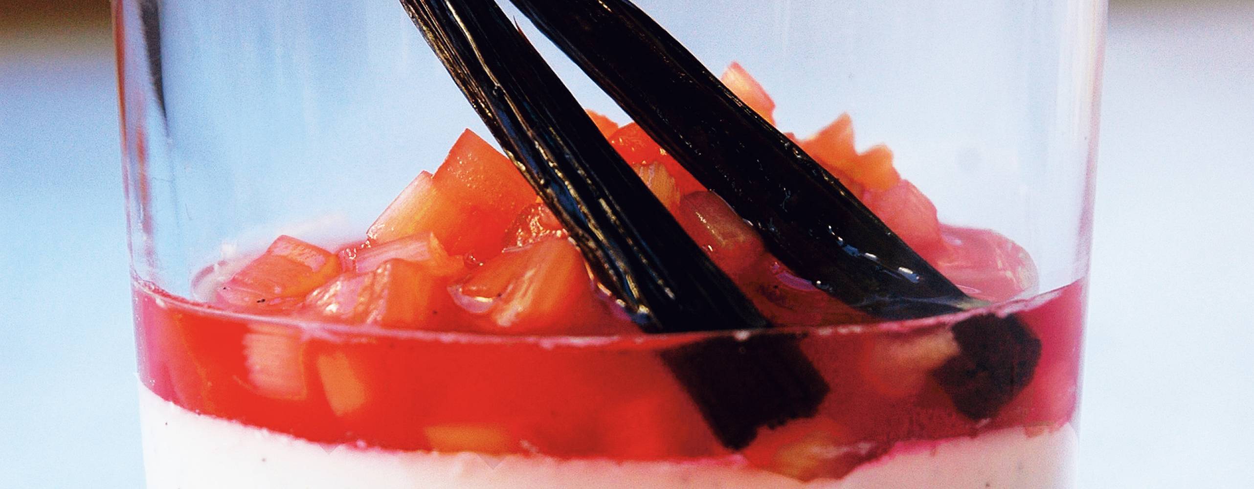 Pannacotta med kokosmjölk och rabarberkompott i ett glas, dekorerad med vaniljstång.