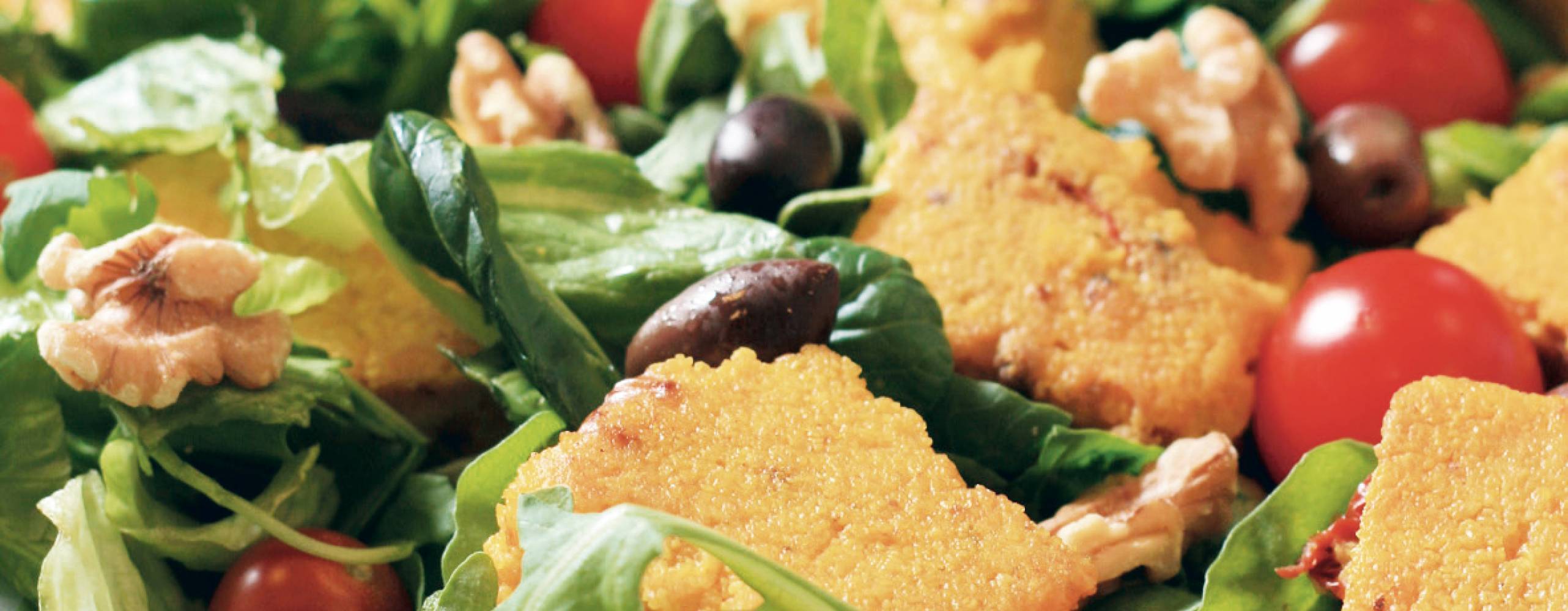 Saffranspolenta med körsbärstomater, oliver, sallad och valnötter på en tallrik