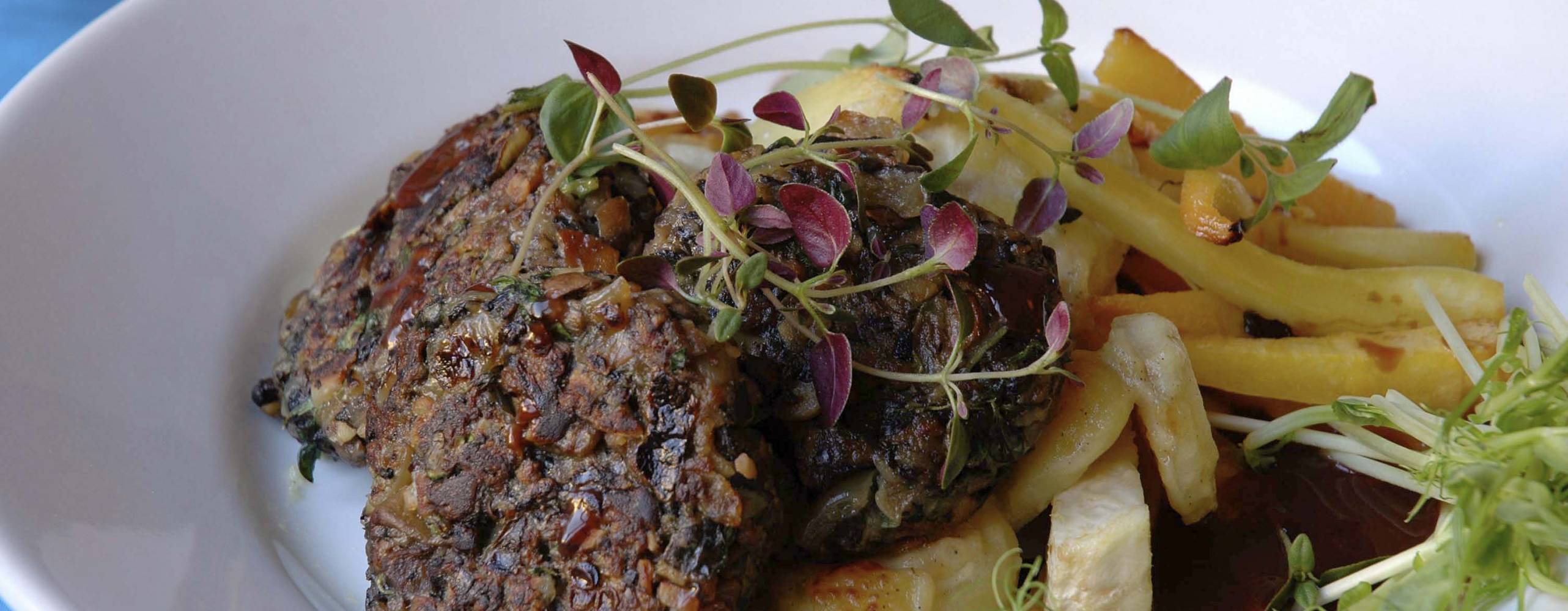 Veganska svampbiffar med sås och potatis på en vit tallrik.