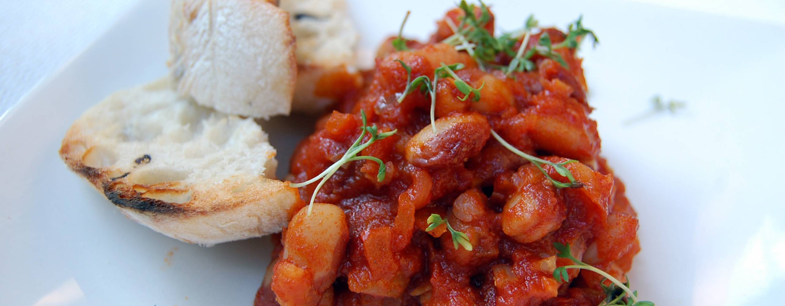 Smokey beans med bröd på en vit tallrik