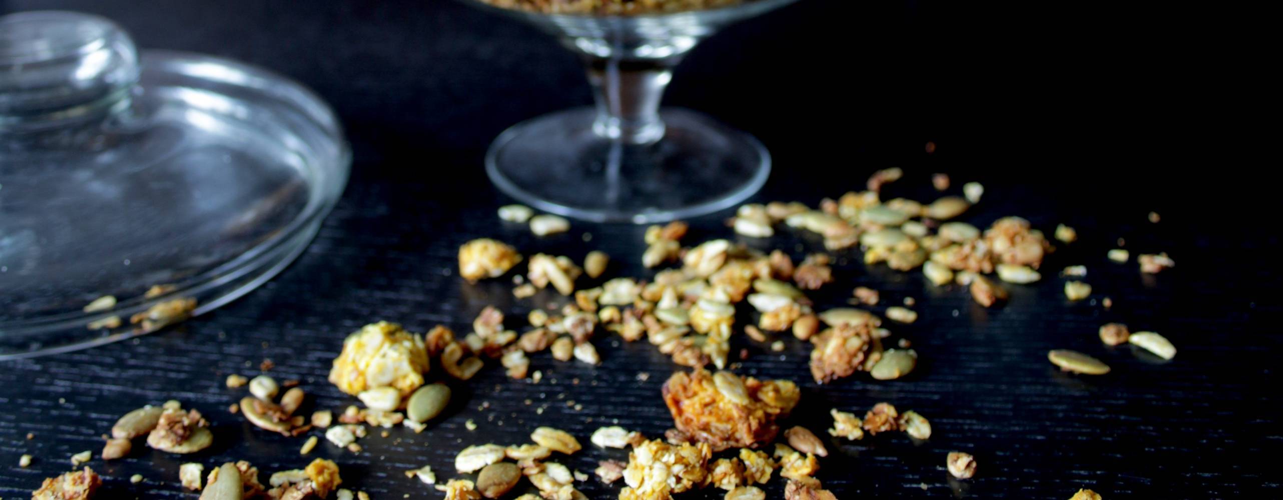 Saffransgranola i en glasbägare på ett mörkt bord.