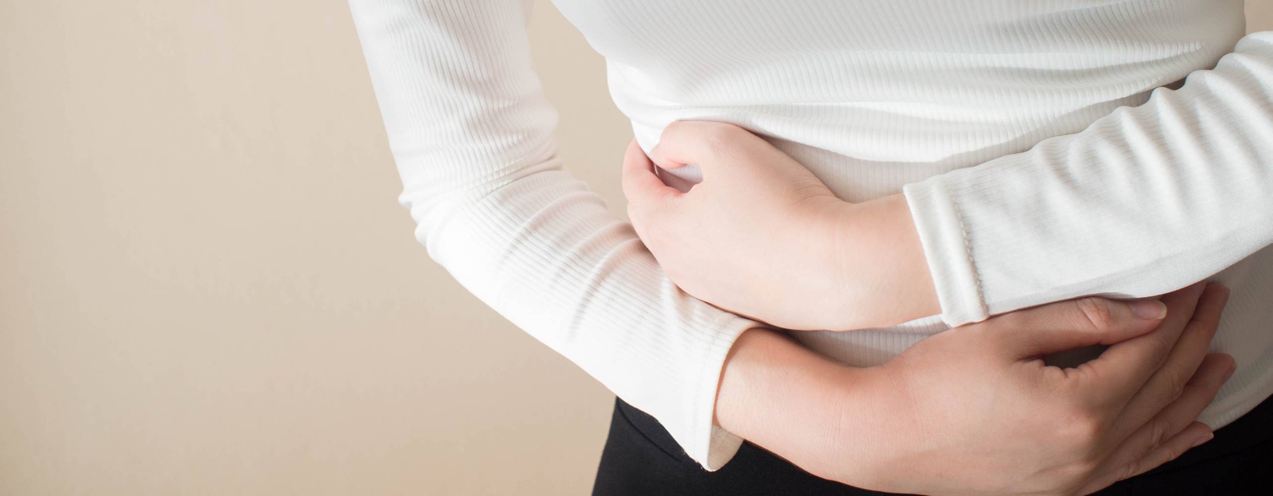 Young female suffering form stomach ache on gray background