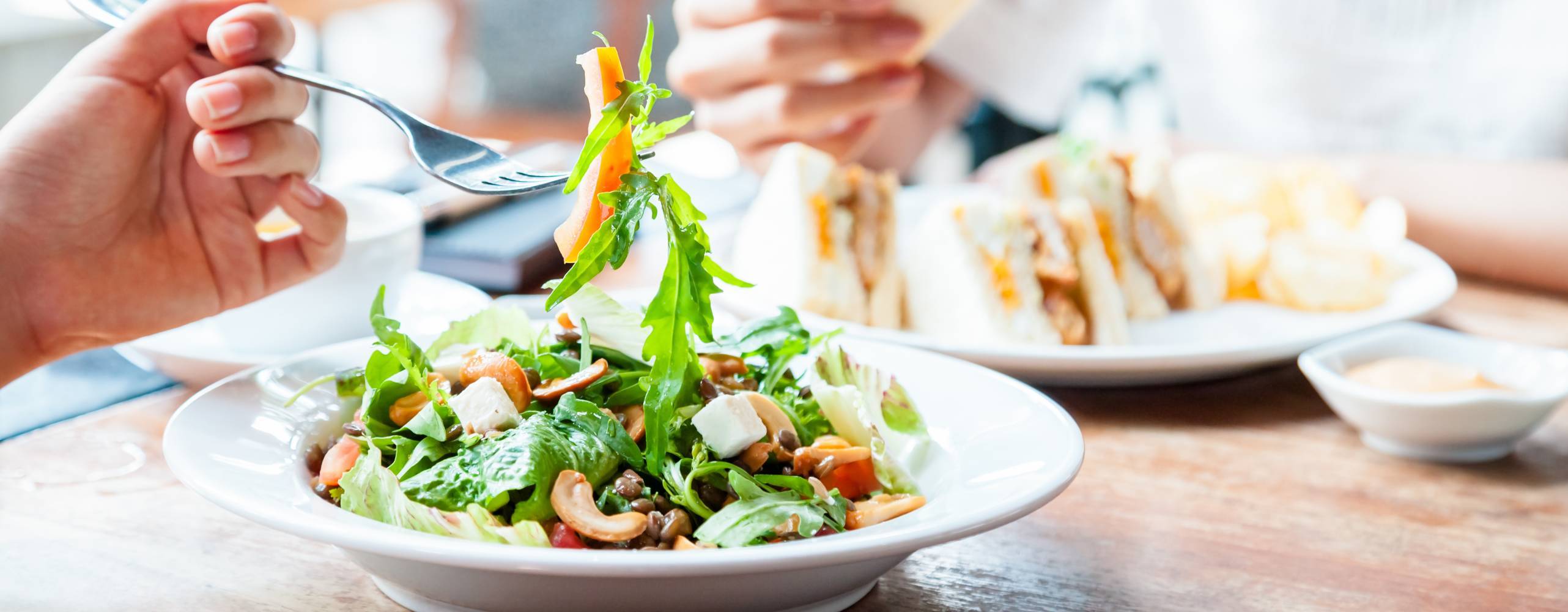 Bild på tallrik med sallad och en person som håller i en gaffel