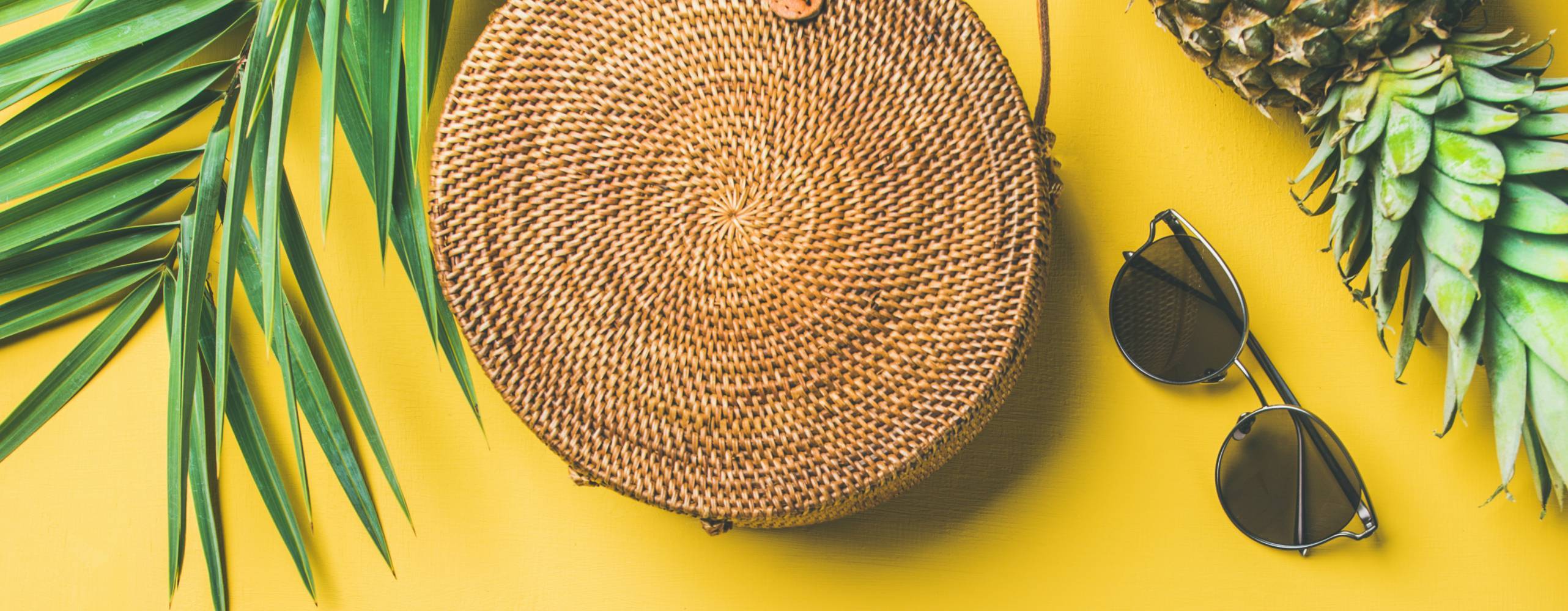 gul bakgrund med en annans, glassögon, väska och palmblad