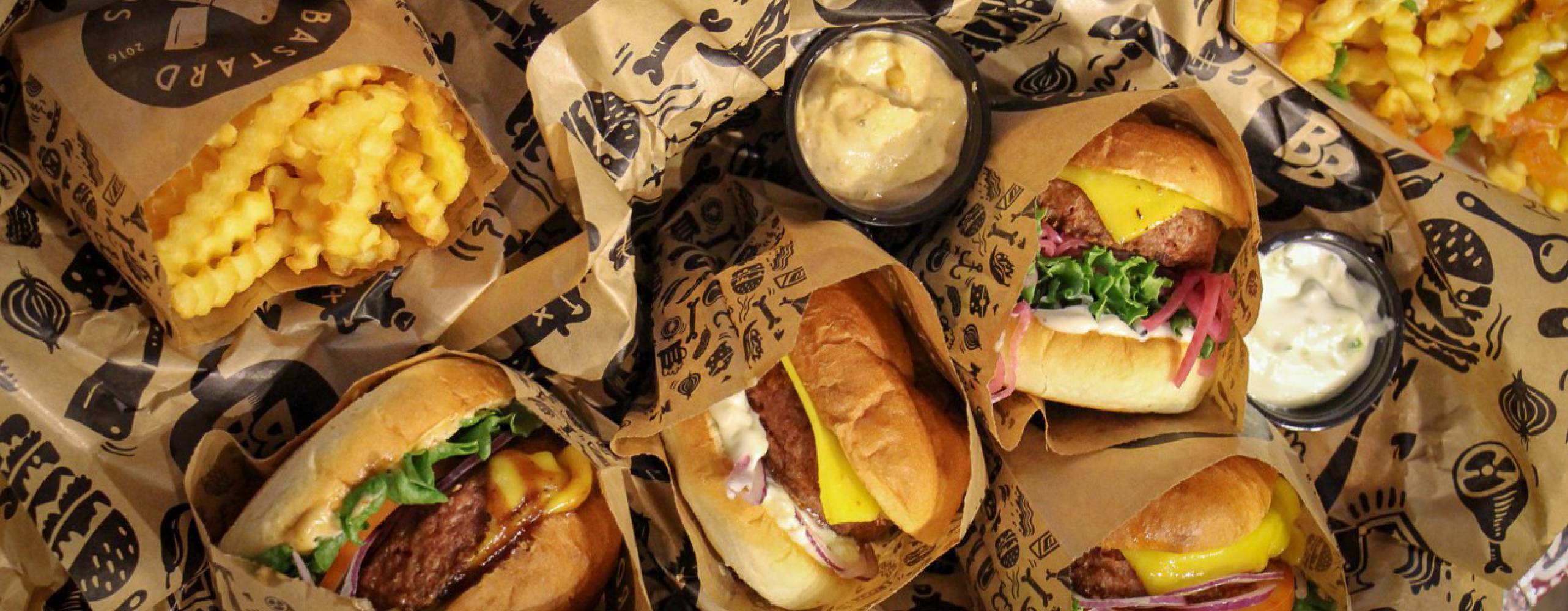 Flera veganska burgare, dressing och pommes på ett bord