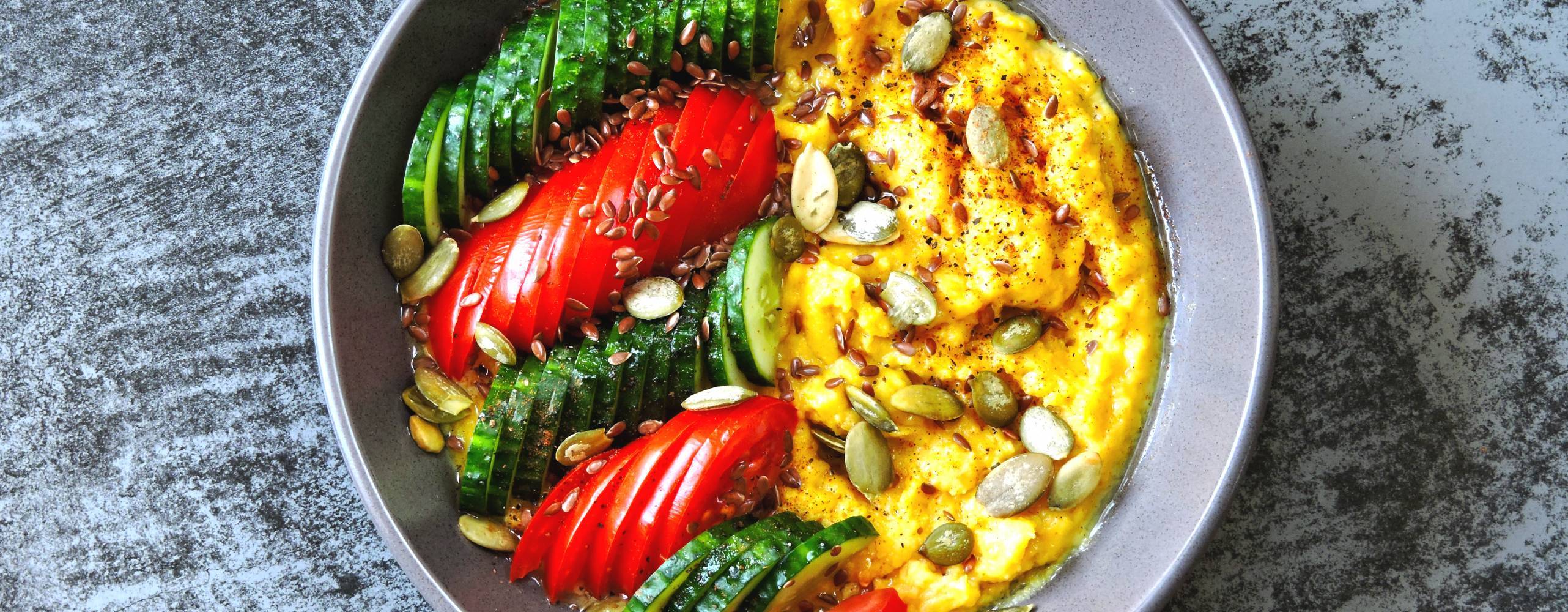 Bowl med grönsaker och polenta på ett bord