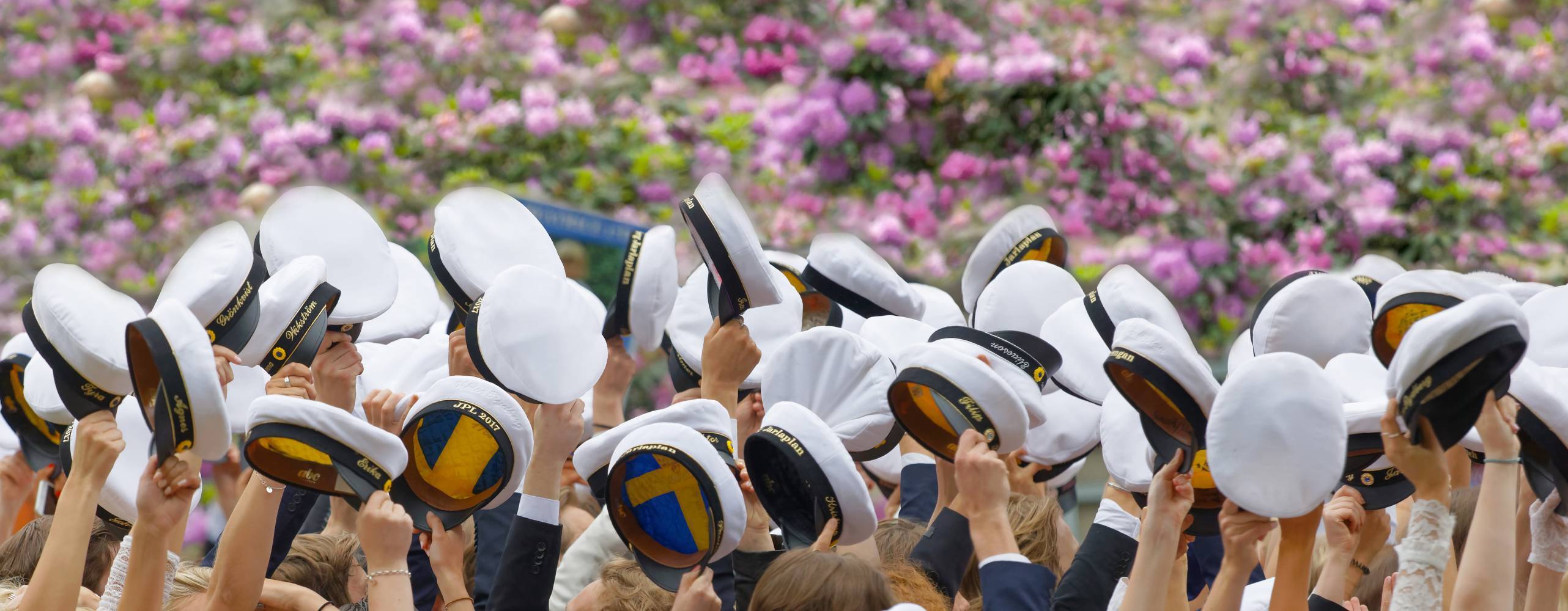 Personer som håller i studentmössa i över huvudet