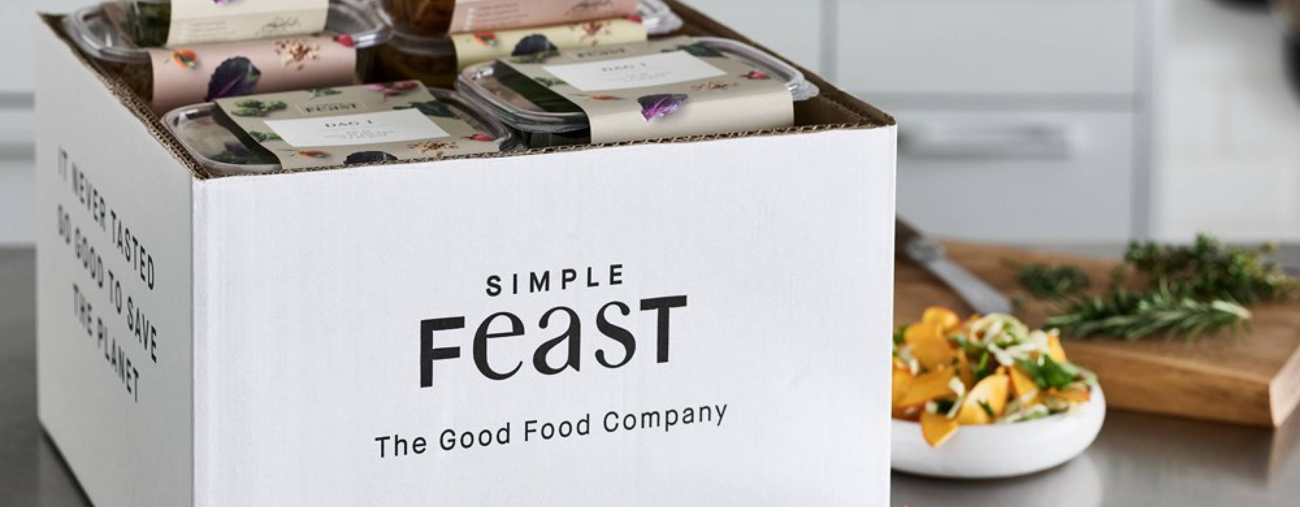 En box fylld av växtbaserade rätter från Simple Feast på en köksbänk.