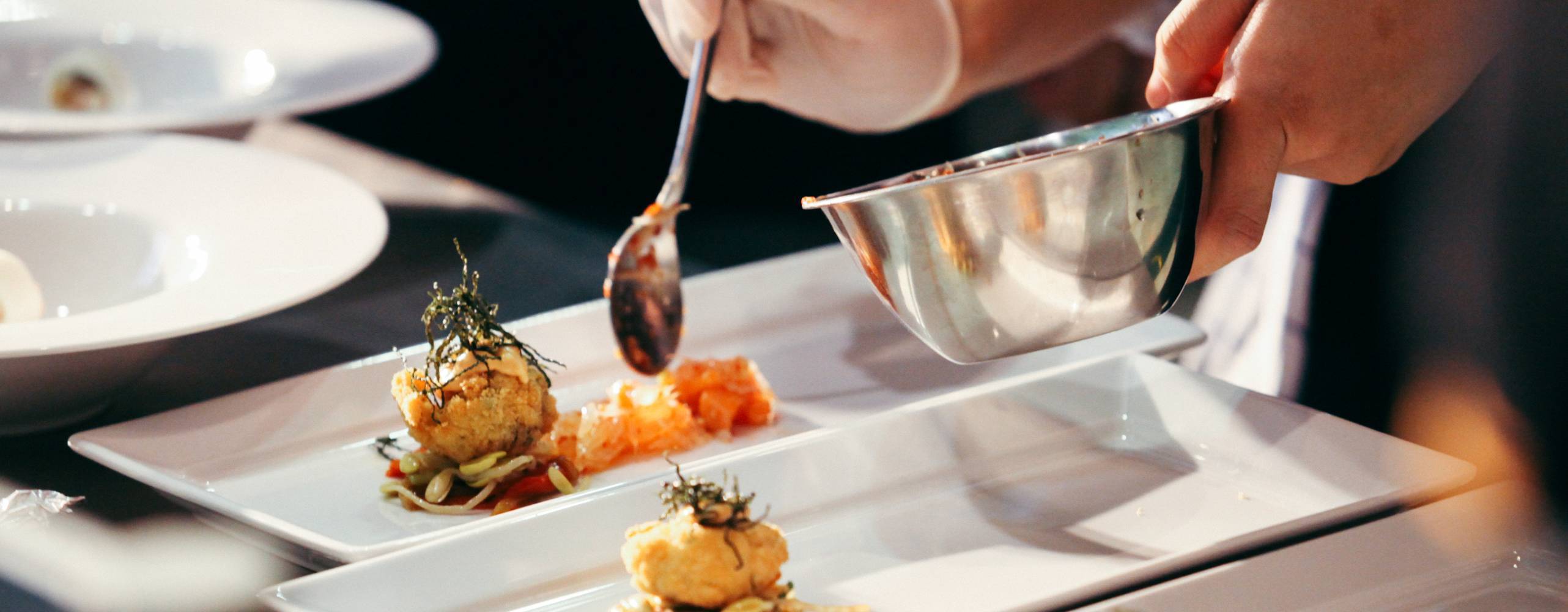 Händer lägger upp mat i en rektangulär tallrik