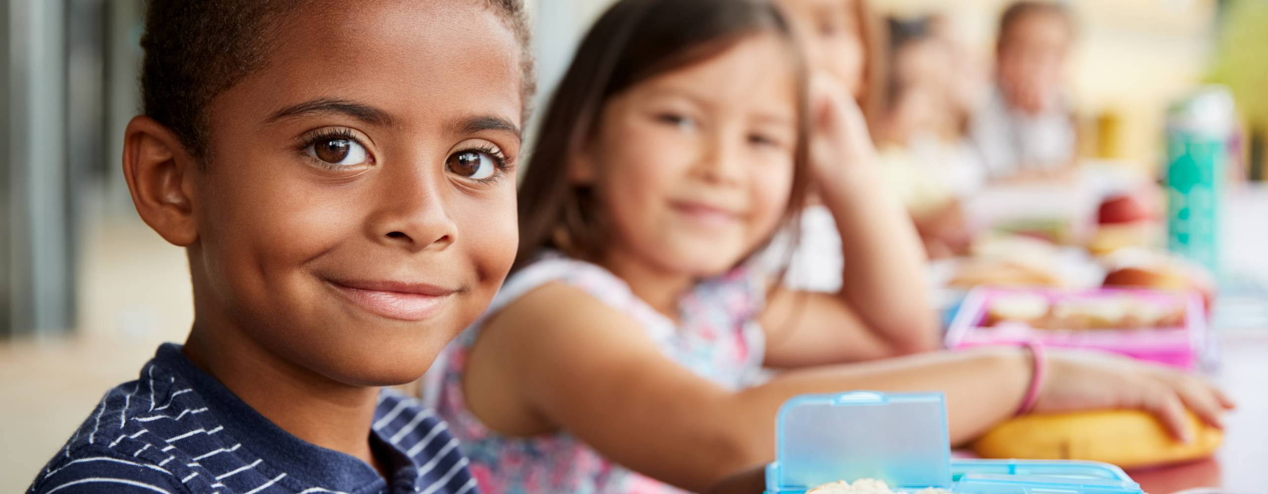 Flera barn sitter på rad, ett barn är i fokus