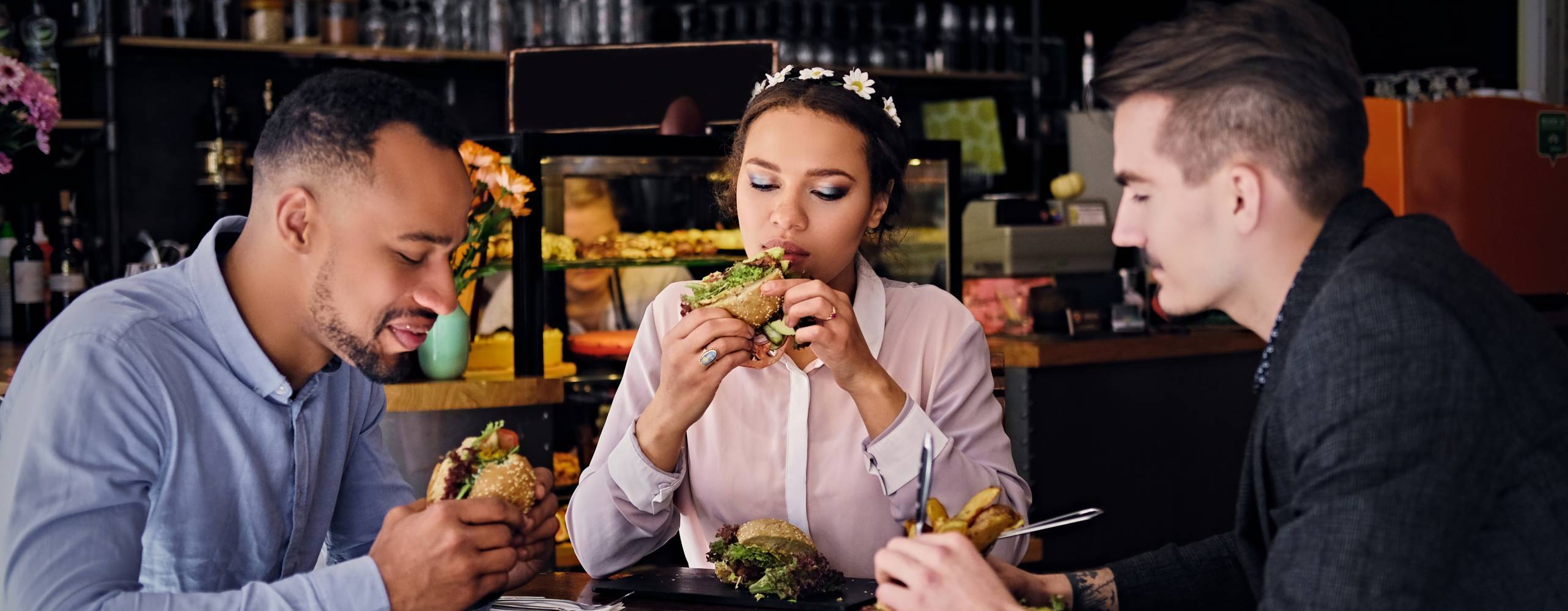 Tre personer sitter och äter på veganska mackor på en pub