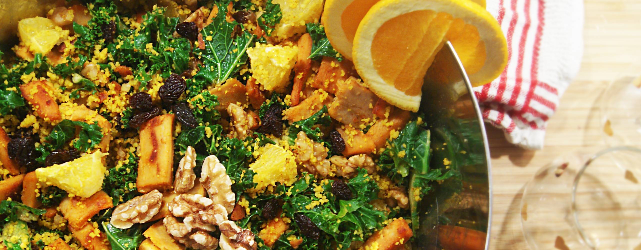 Grönkålssallad med saffranscouscous, apelsin, valnötter och russin i en skål.