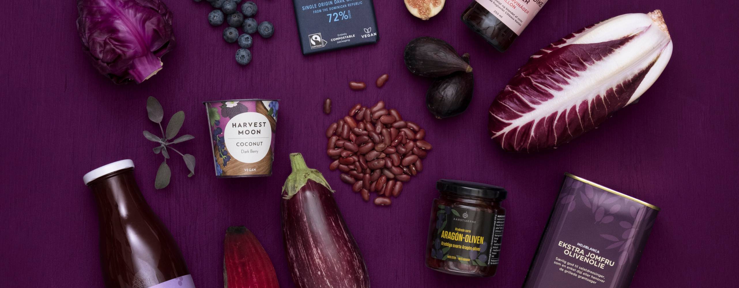 Växtbaserade produkter i lila och svarta toner utlagda på purpurfärgad yta.