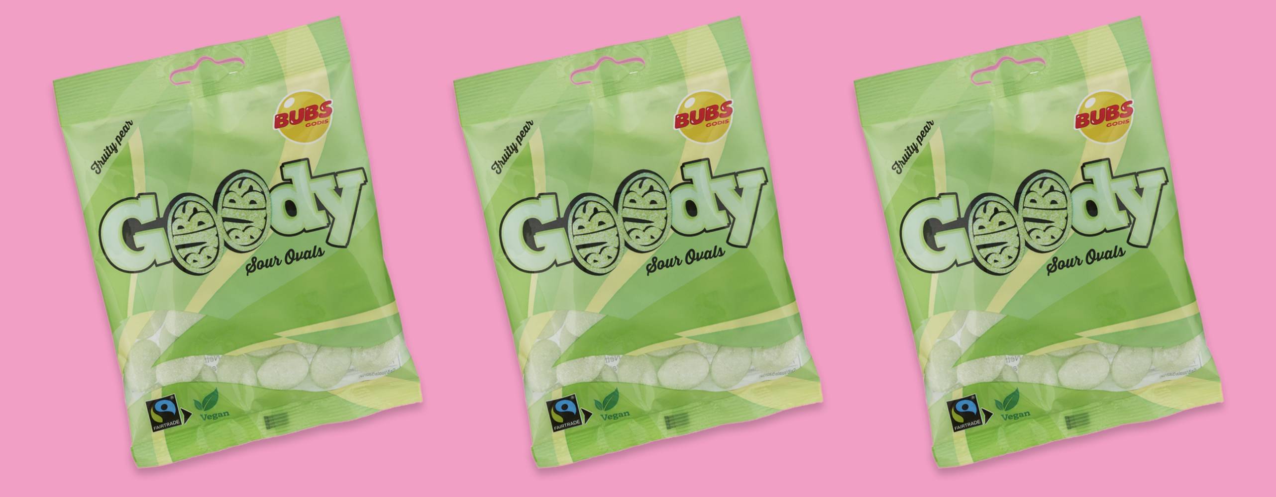 Tre gröna godispåsar uppradade mot en rosa bakgrund.