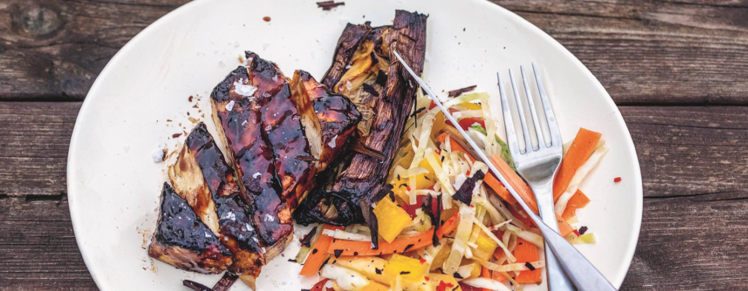 Grillad sticky tofu upplagt på en tallrik tillsammans med rivna rotfrukter.