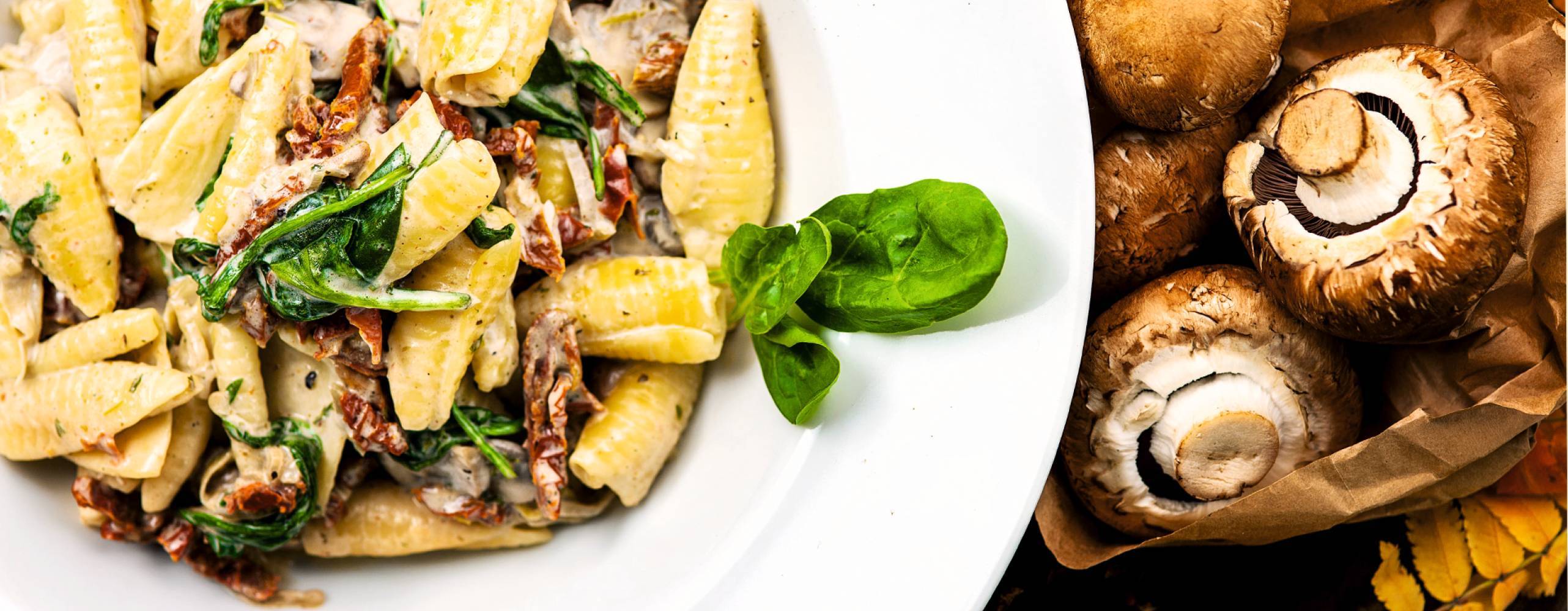 En vit djuptallrik med krämig pasta med svamp och basilika.