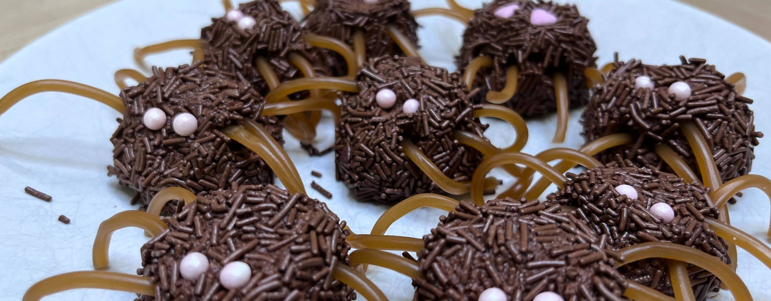 Chokladbollar som ser ut som spindlar med kolaremmar som ben och strössel som ögon