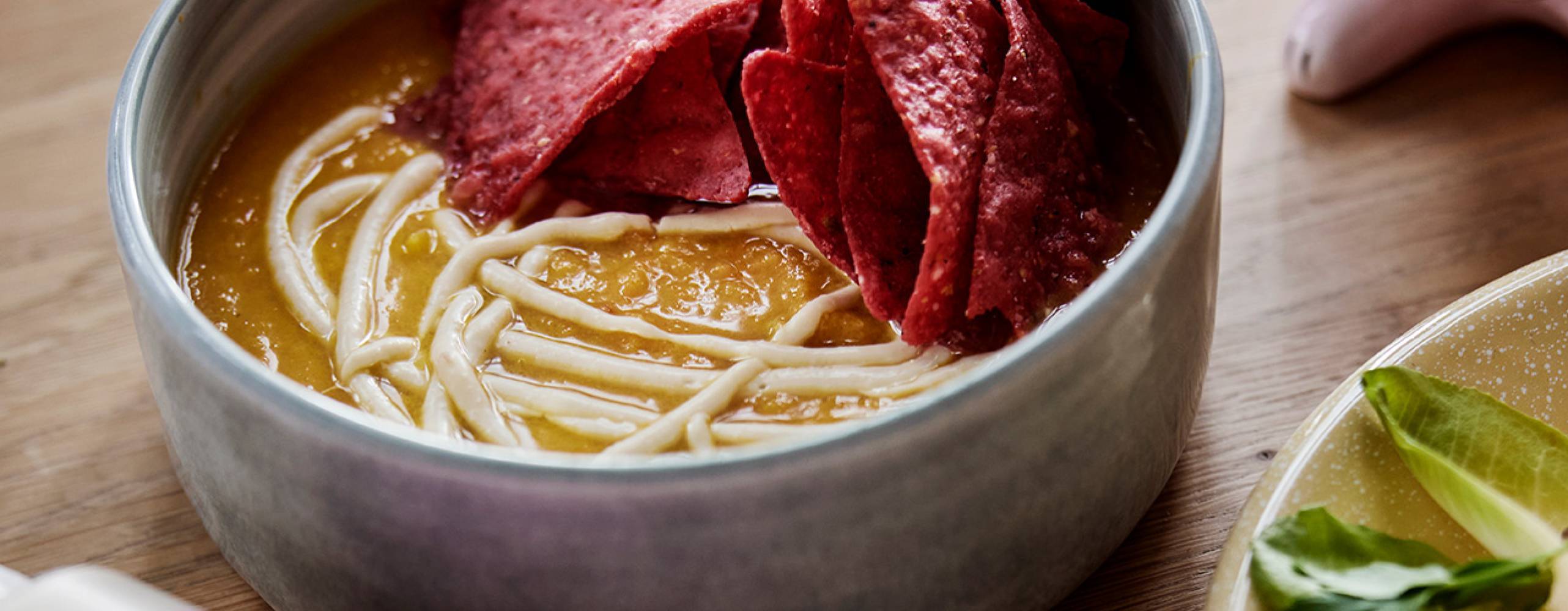 Pumpasoppa i en skål med nachos på sidan om soppan.