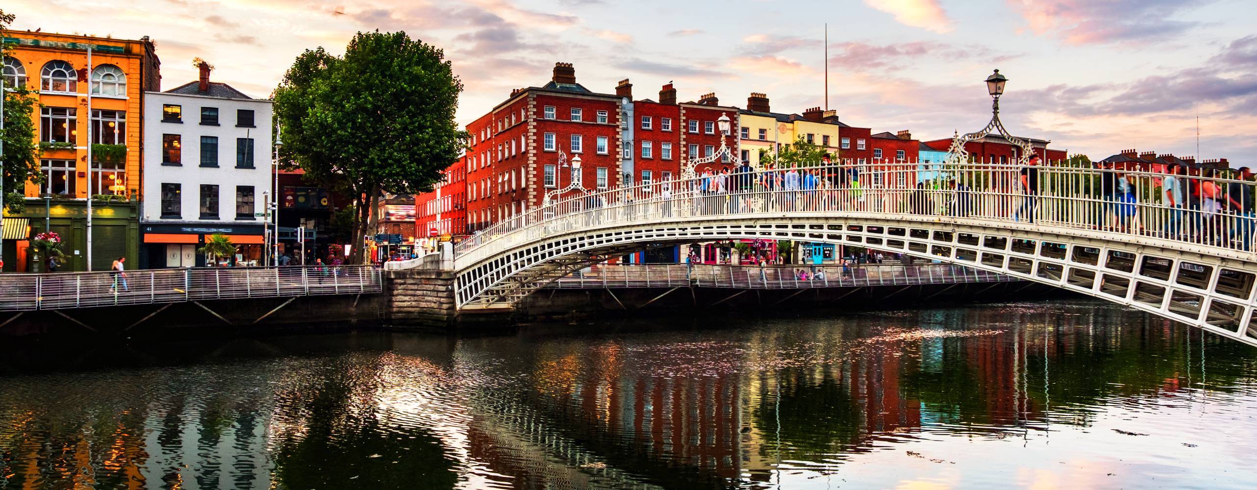 Dublin, Irland. Nattutsikt över berömda upplysta Ha Penny Bridge i Dublin, Irland vid solnedgången.