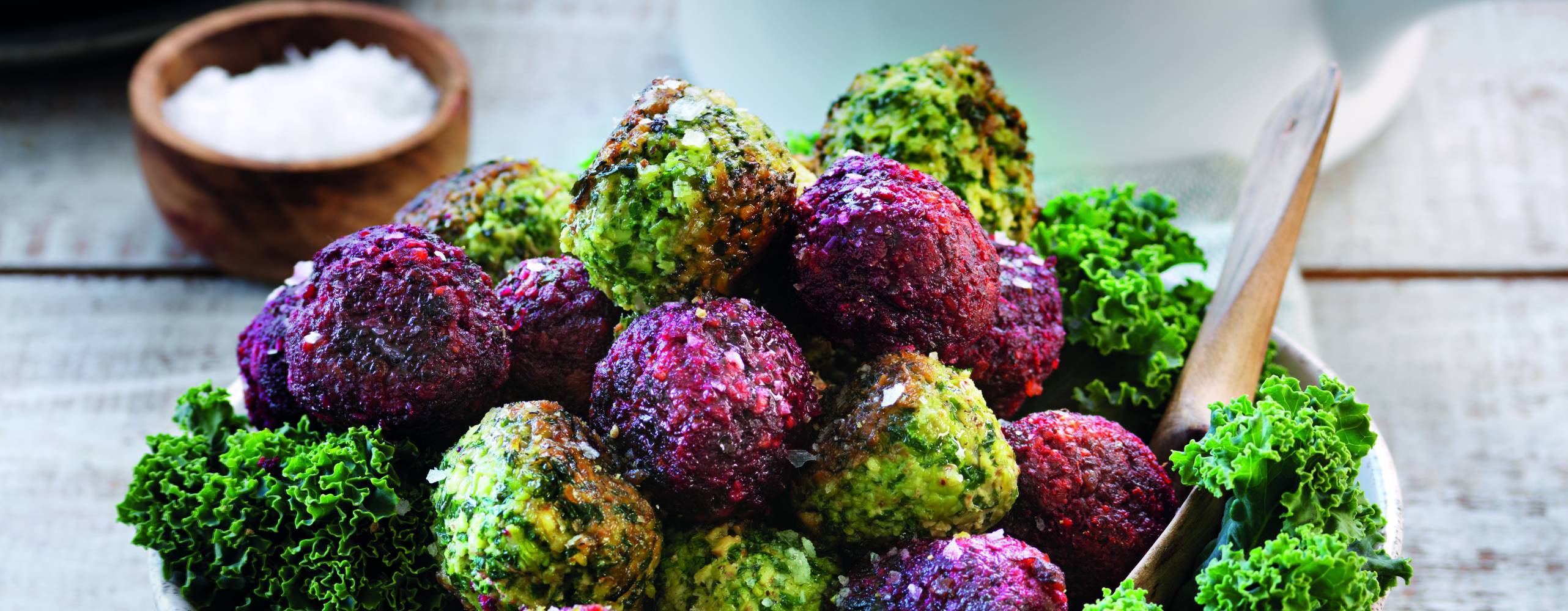 En skål med gröna och lila bollar på grönkål och rödbetor