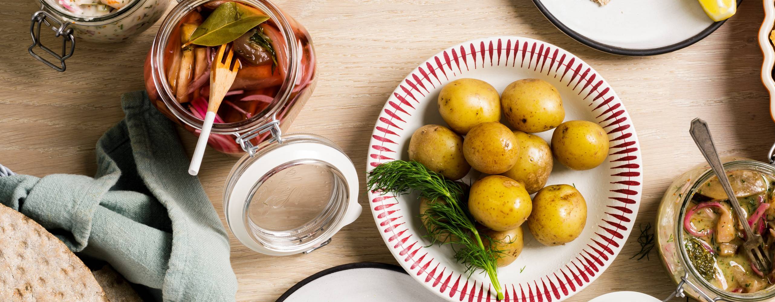 Flera olika veganska sillar uppdukade på ett bord med kokt potatis och knäckebröd.