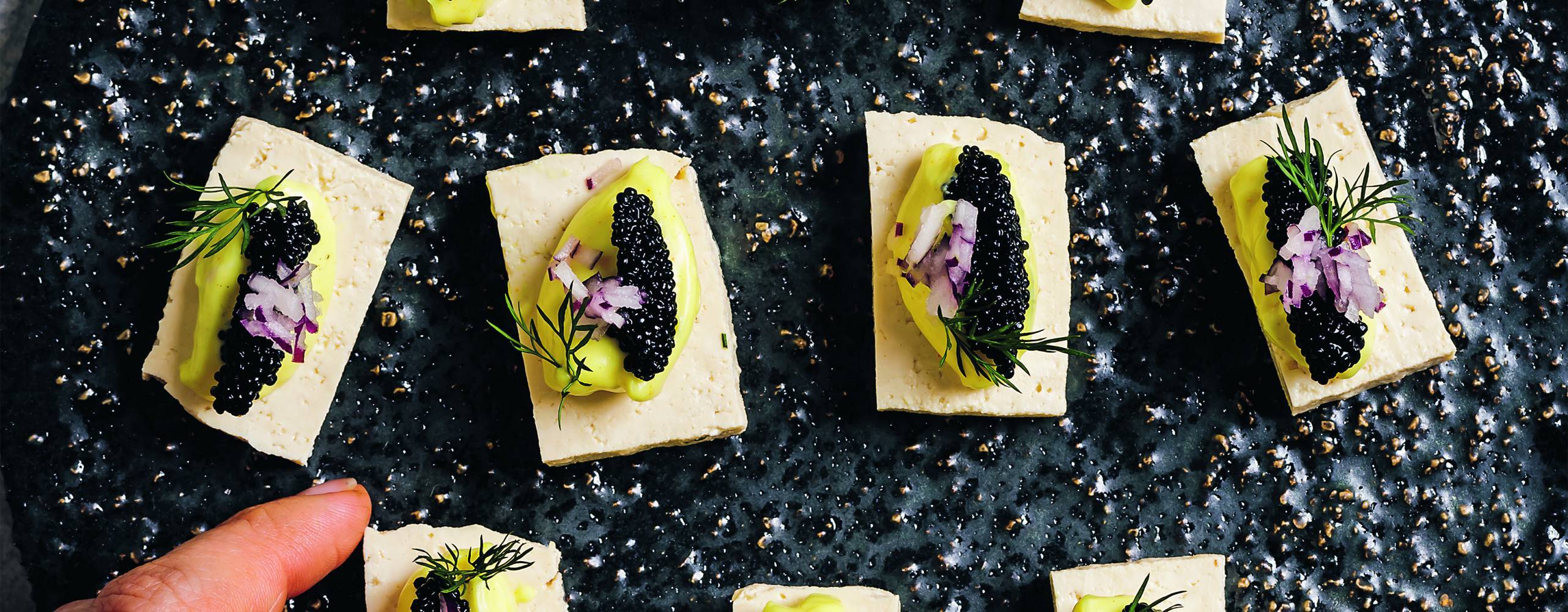 Små uppskurna tofurektanglar med majonnäs och tångrom på ett svart fat