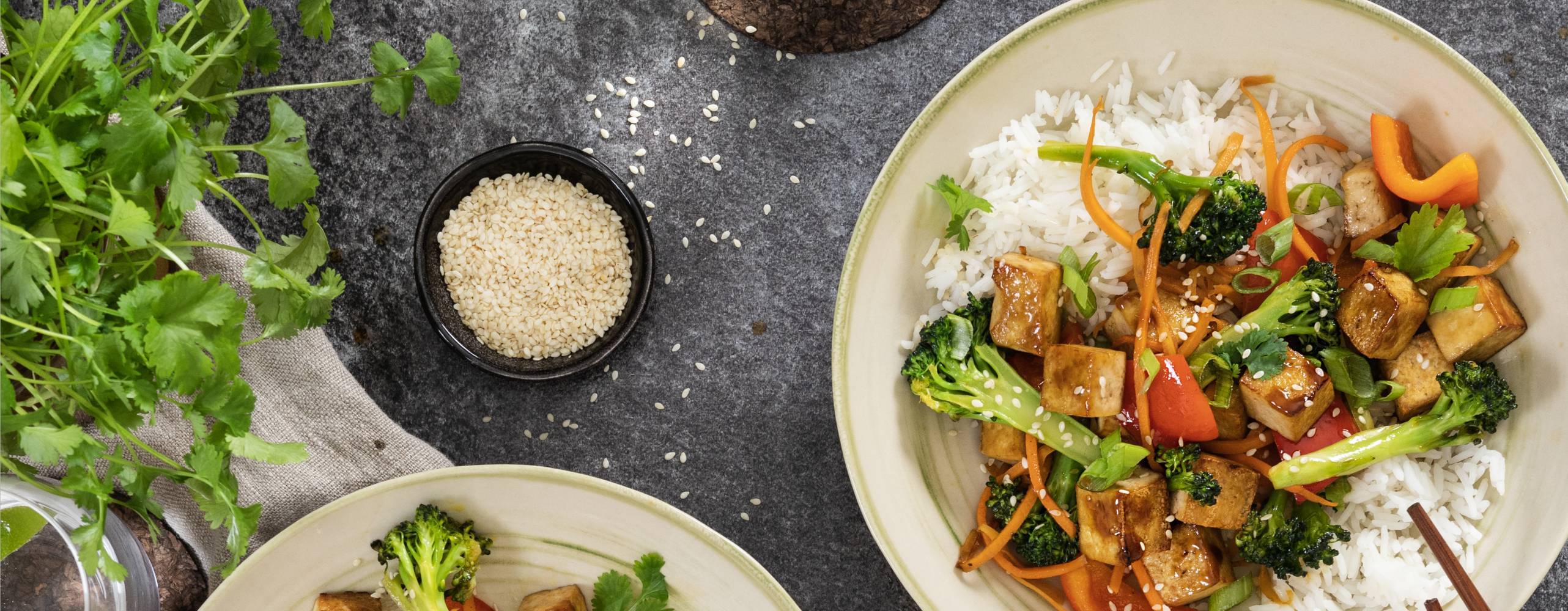 Wok med ros i två tallrikar taget ovanifrån mot ett grått bord