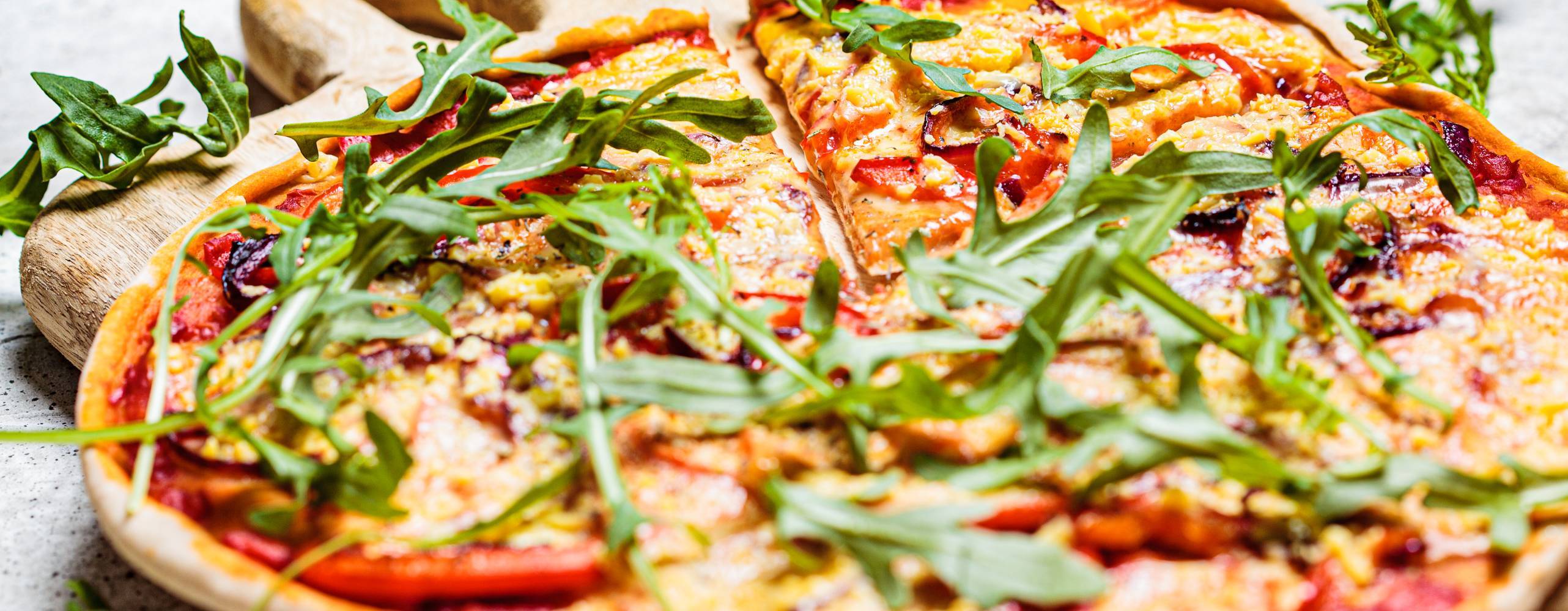 Vegan pizza with tomato sauce, pepper, vegan cheese and arugula. Healthy vegan food concept.