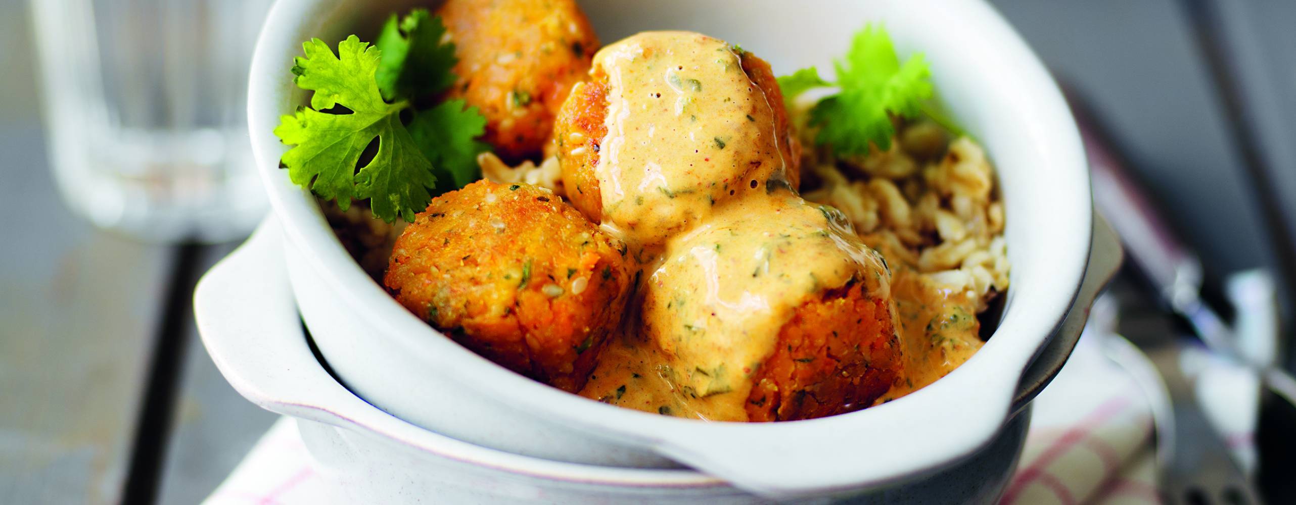 Majsbollar i en vit skål på en kökshandduk på ett träbord