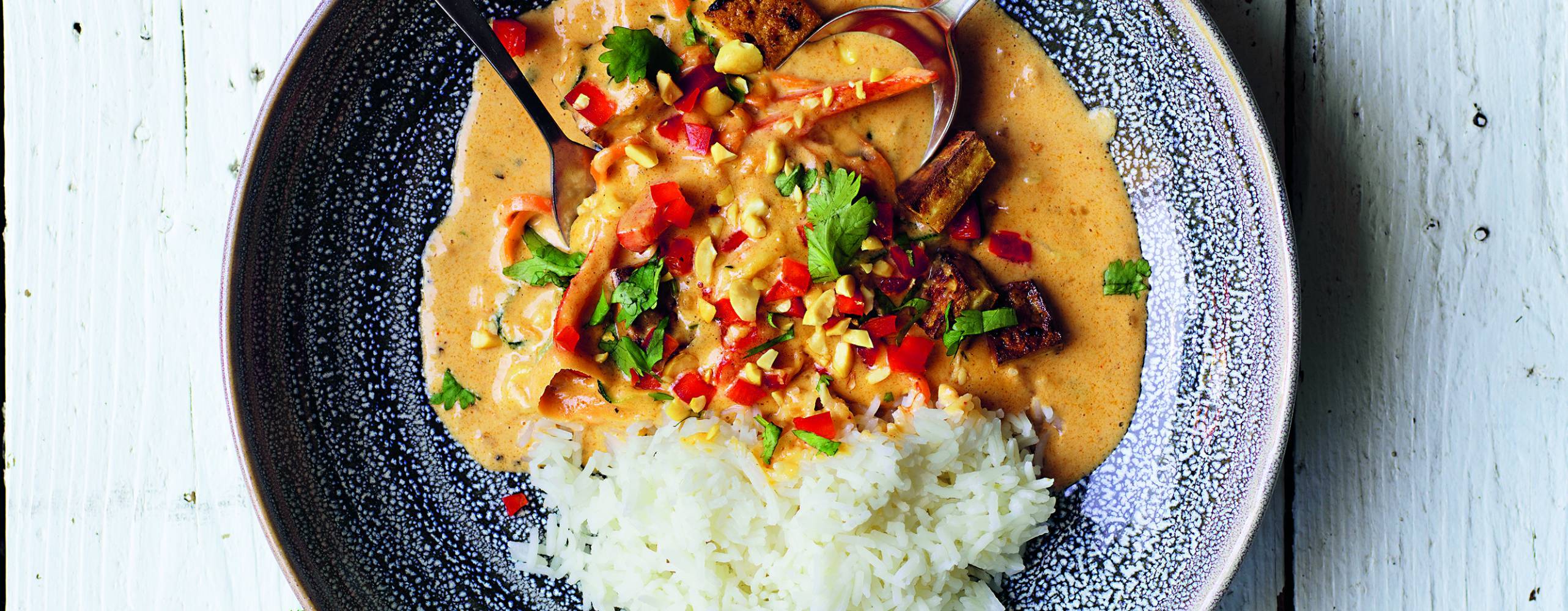 Jordnötsgryta med tofu i en djuptallrik på ett vitt bord