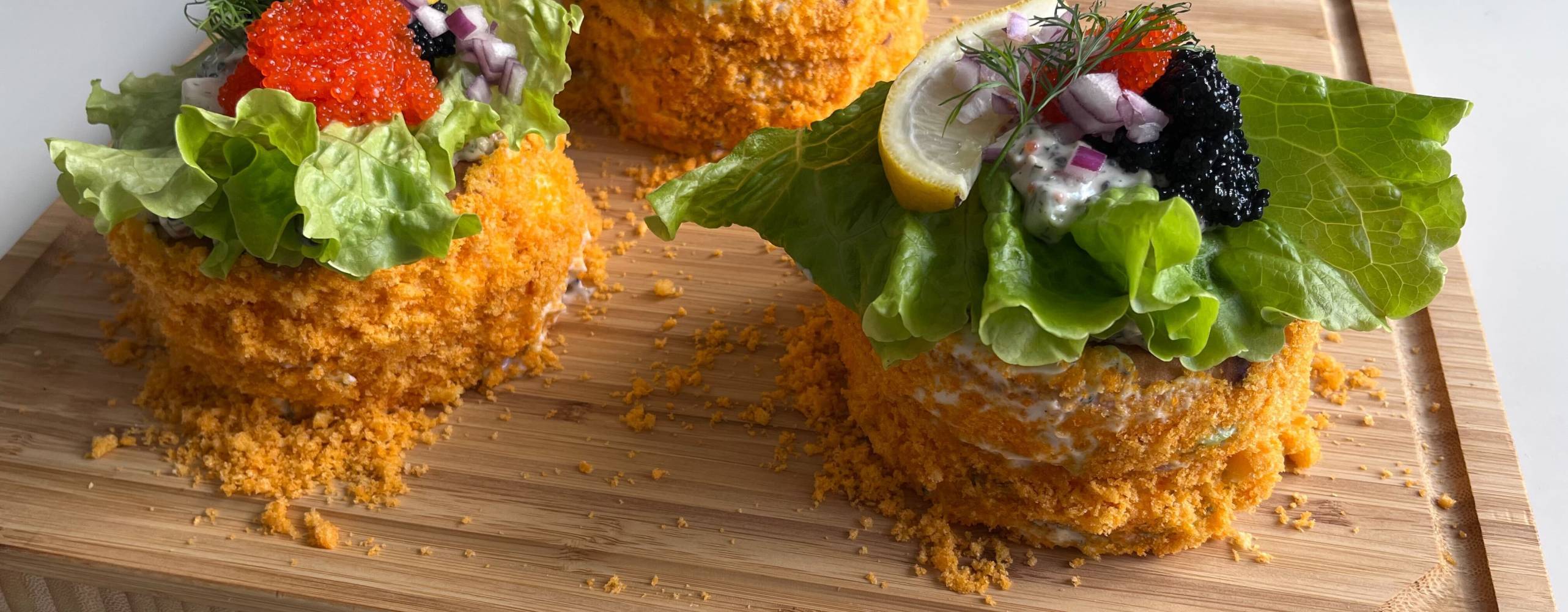 Tre runda minismörgåstårtor på en skärbräda i trä