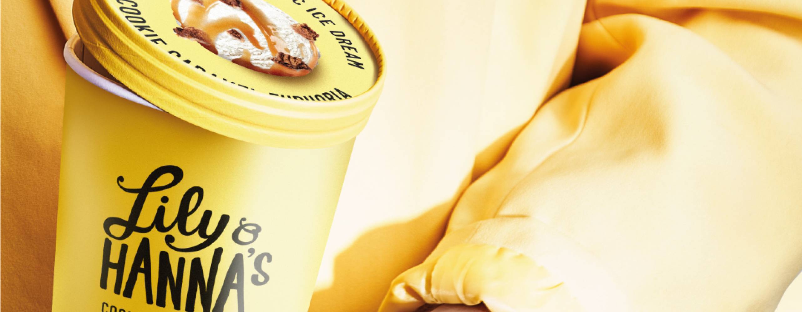 Kvinna i gula kläder som håller en gul glassbytta med en sked med glass i handen