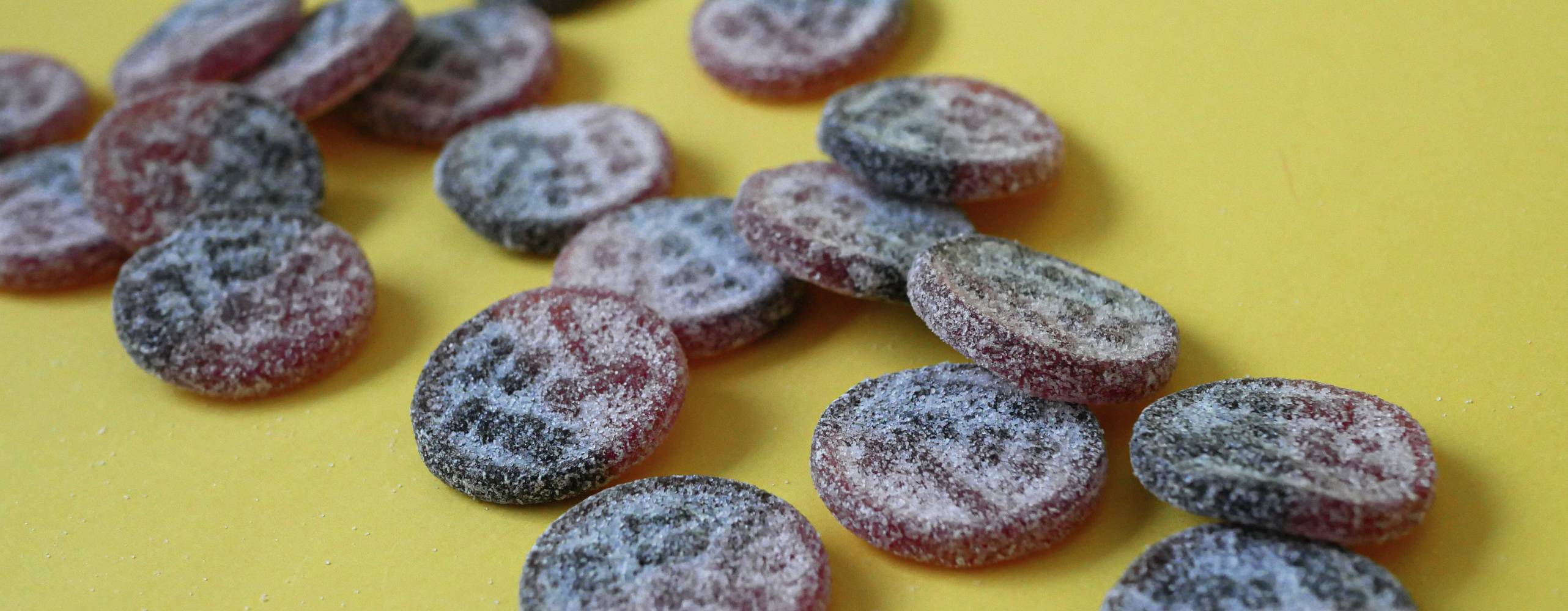 utspridda lakritsgodisar på ett gult underlad