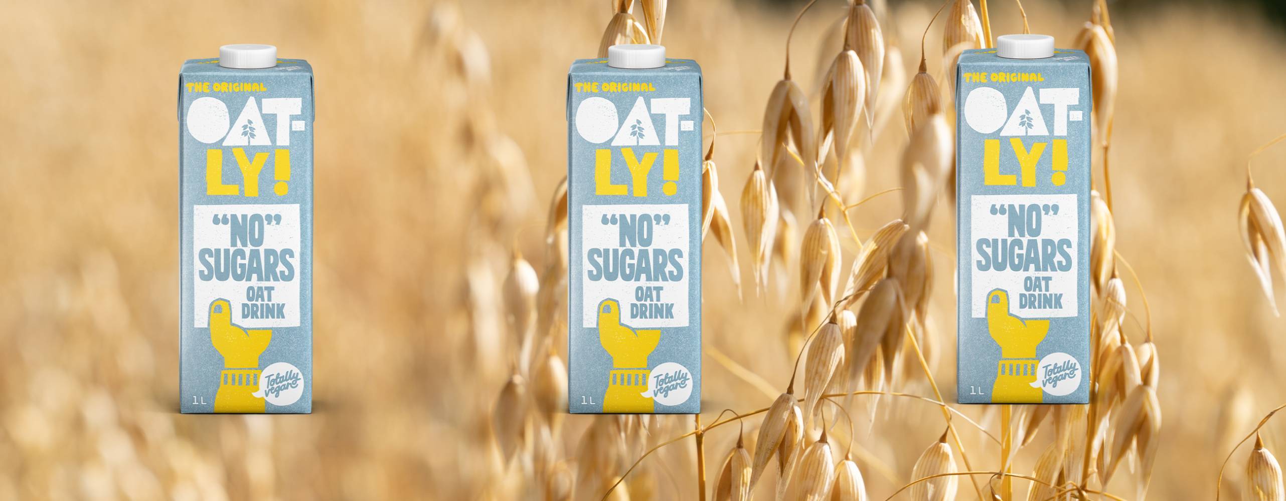 tre förpackningar havredryck mot en bakgrund som är ett havrefält