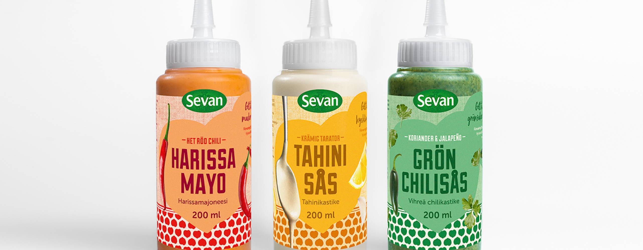 Tre flaskor med vegansk sås uppstaplade mot en vit bakgrund