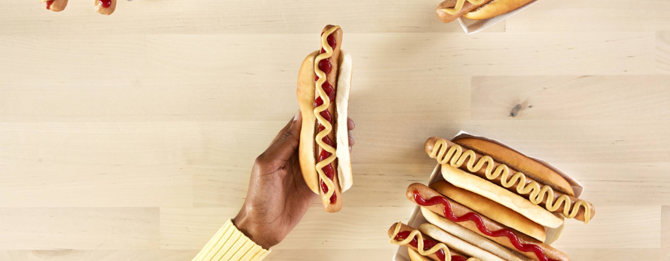 9 veganska varmkorvar och en hand mot ett bord i björk