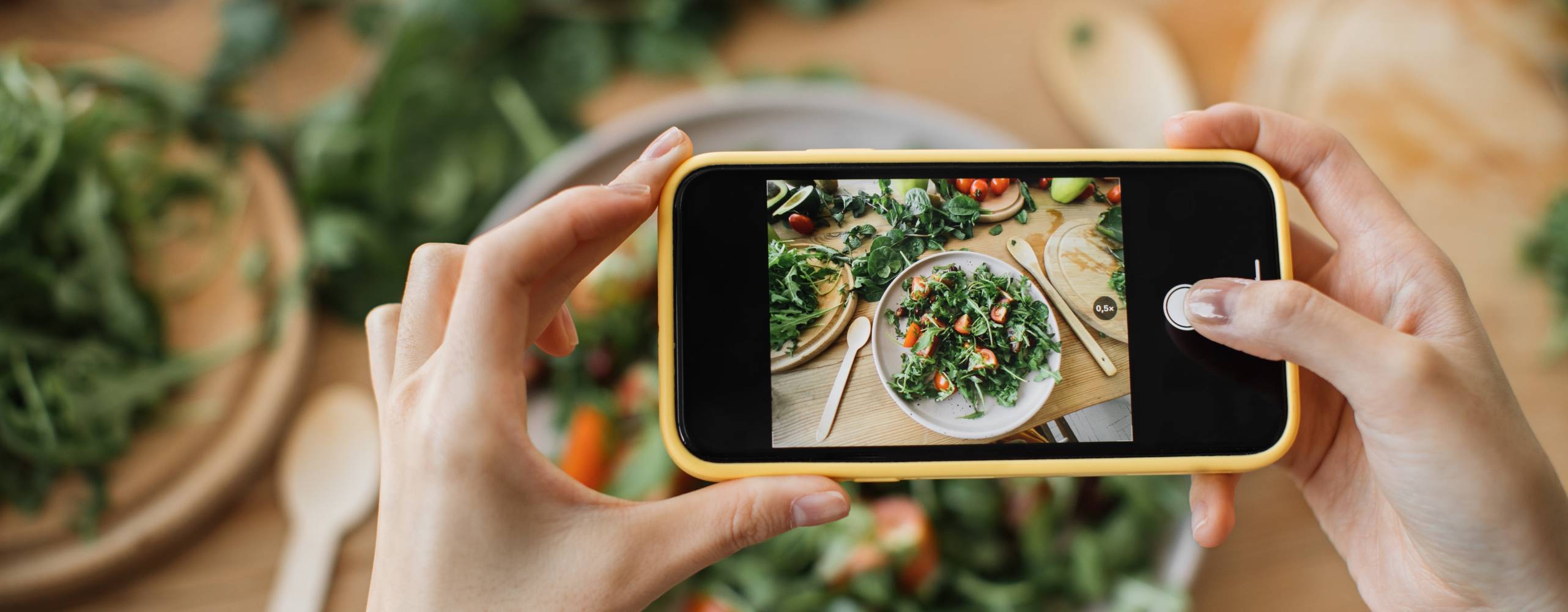 Kvinnahänder tar telefonfoto av matlunch eller middag. Grönsakssallad, avokado, ruccolatomater. Smartphonefotografering för sociala nätverk. Vegetarisk hälsosam mat.