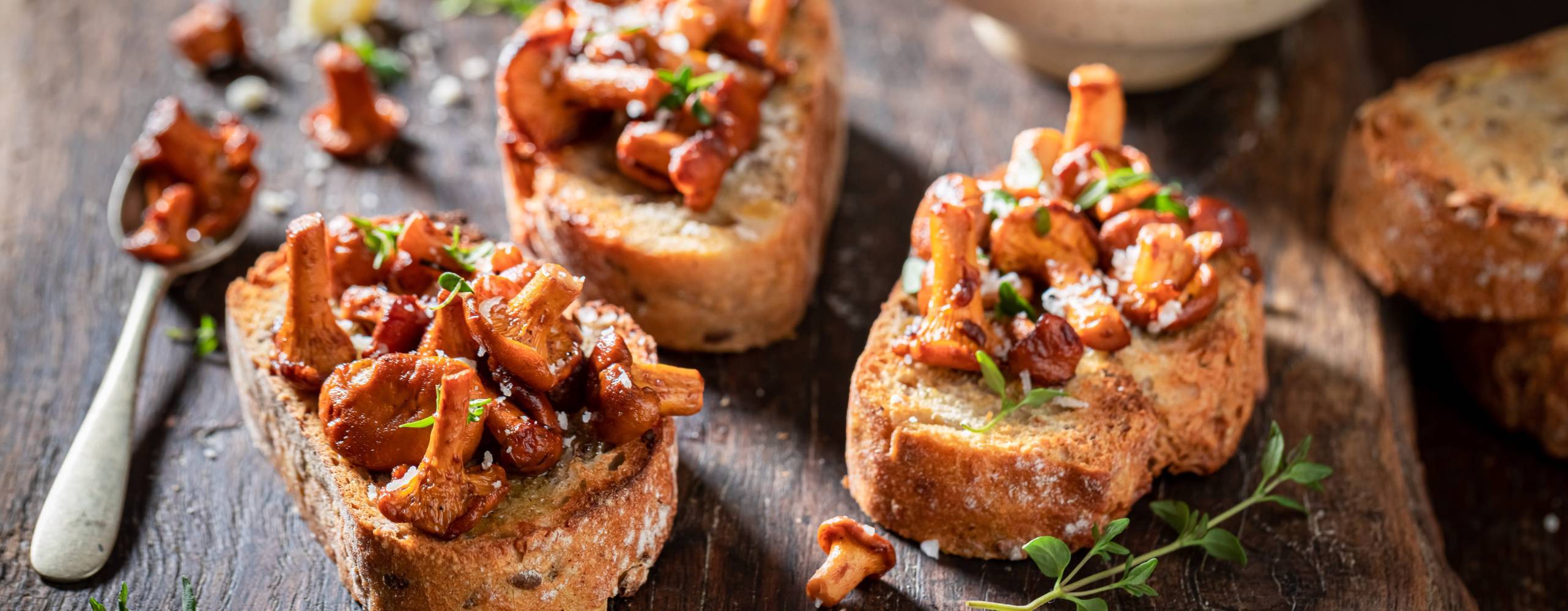 Tre kantarellmackor på en skärbräda i trä