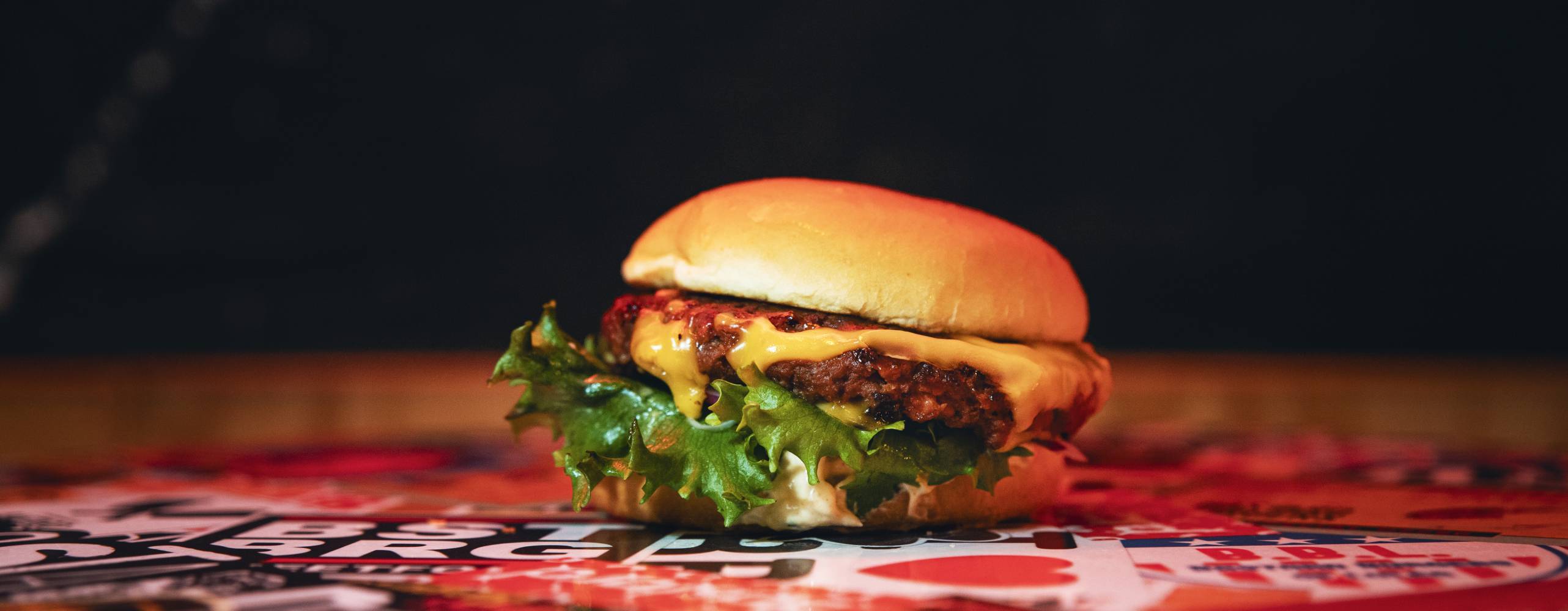 En vegansk hamburgare på ett färgglatt bord och en mörk bakgrund