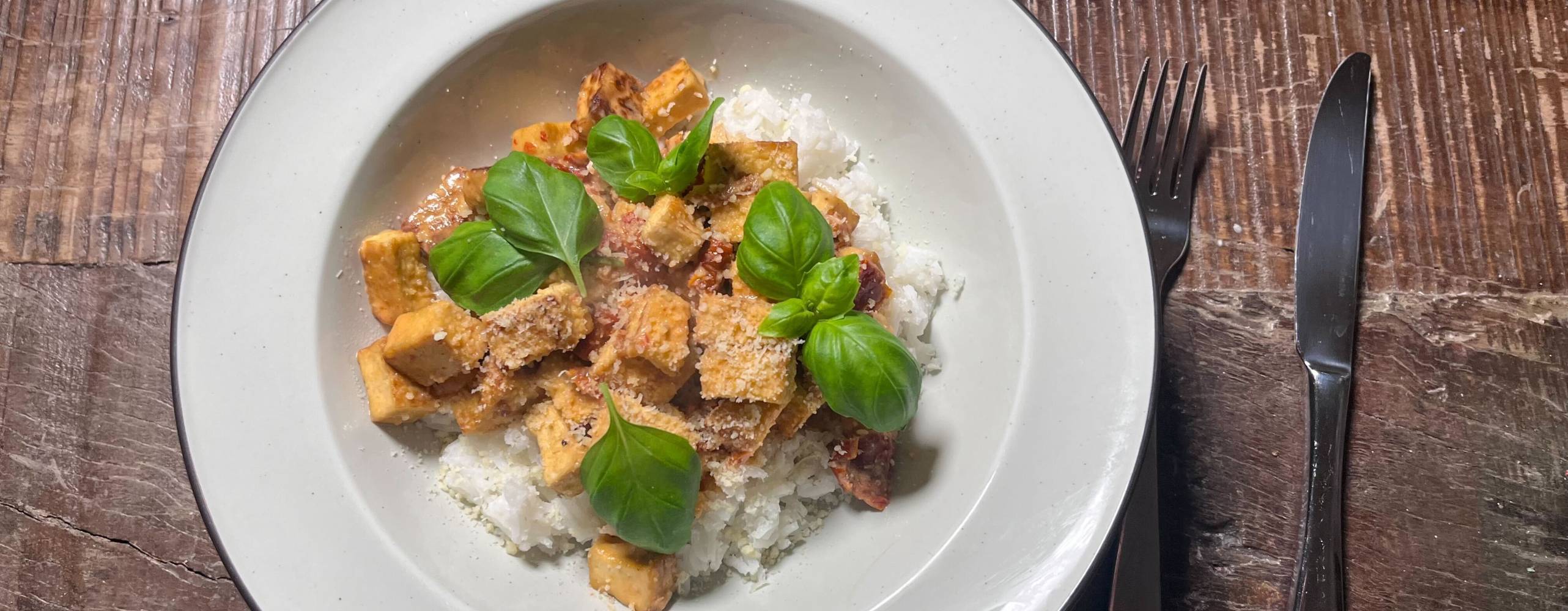 En tallrik med ris och tofu, garnerad med basilika.