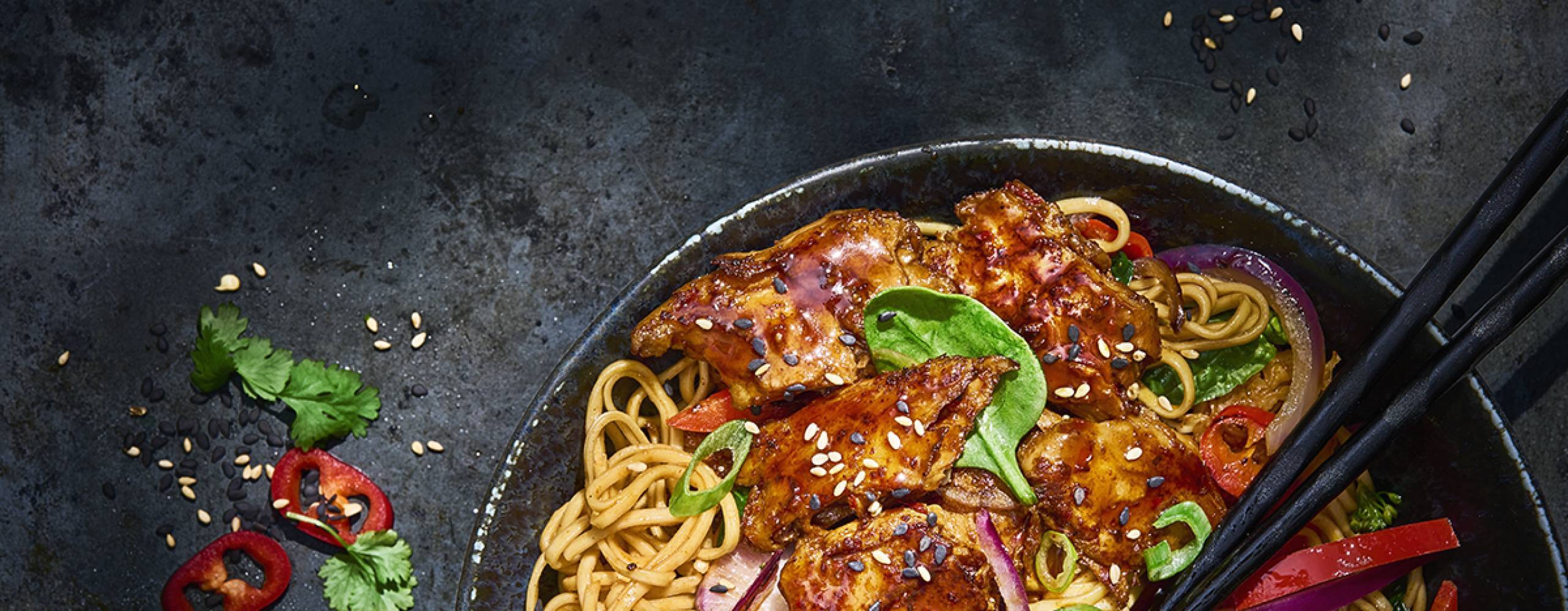 Koreansk nudelwok i en svart tallrik på ett svart bord