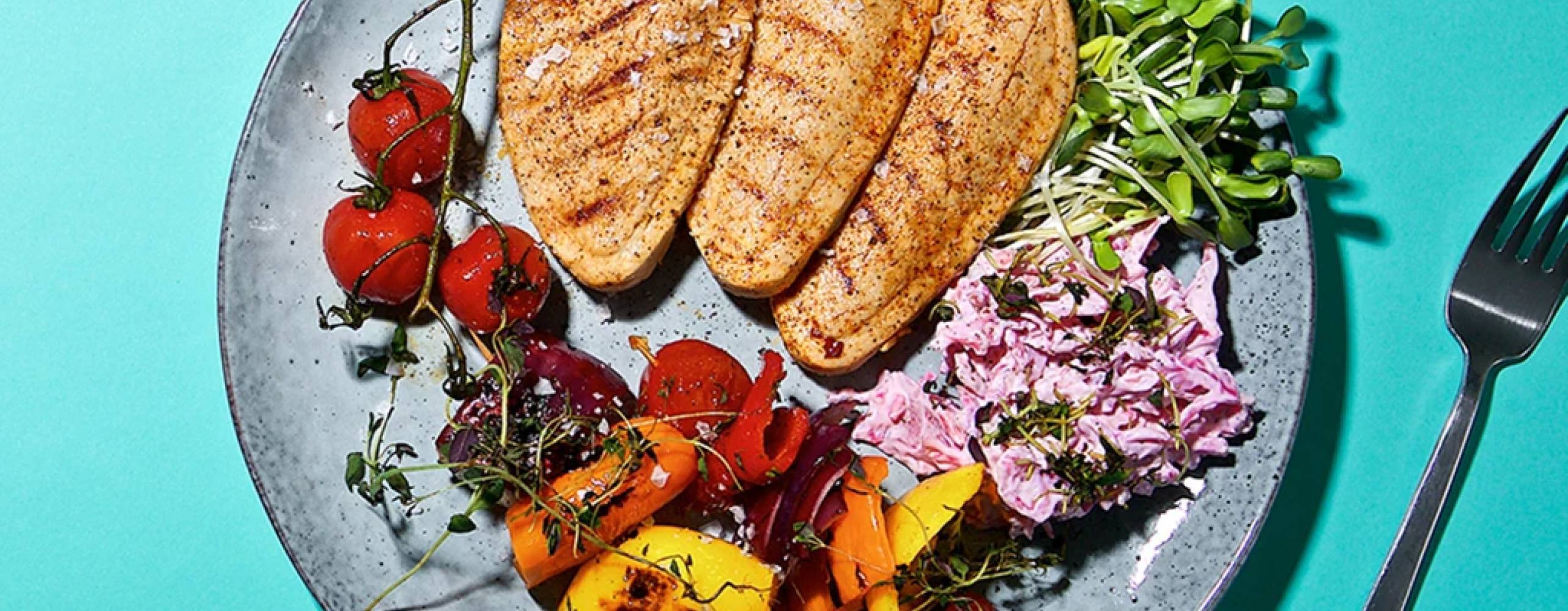 tre vegofiléer med grönsaksspett och coleslaw på en tallrik, på ett turkost bord