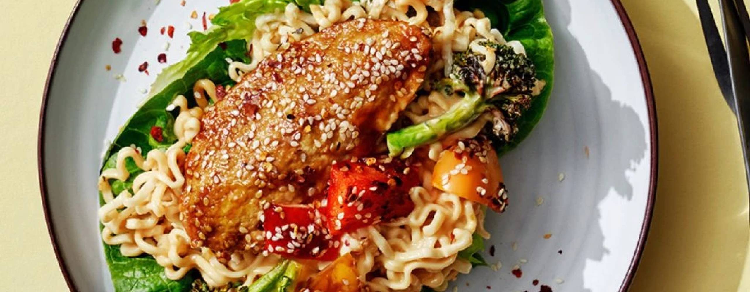 Vegofiléer med med nudlar och sallad på en tallrik, på ett gult bord