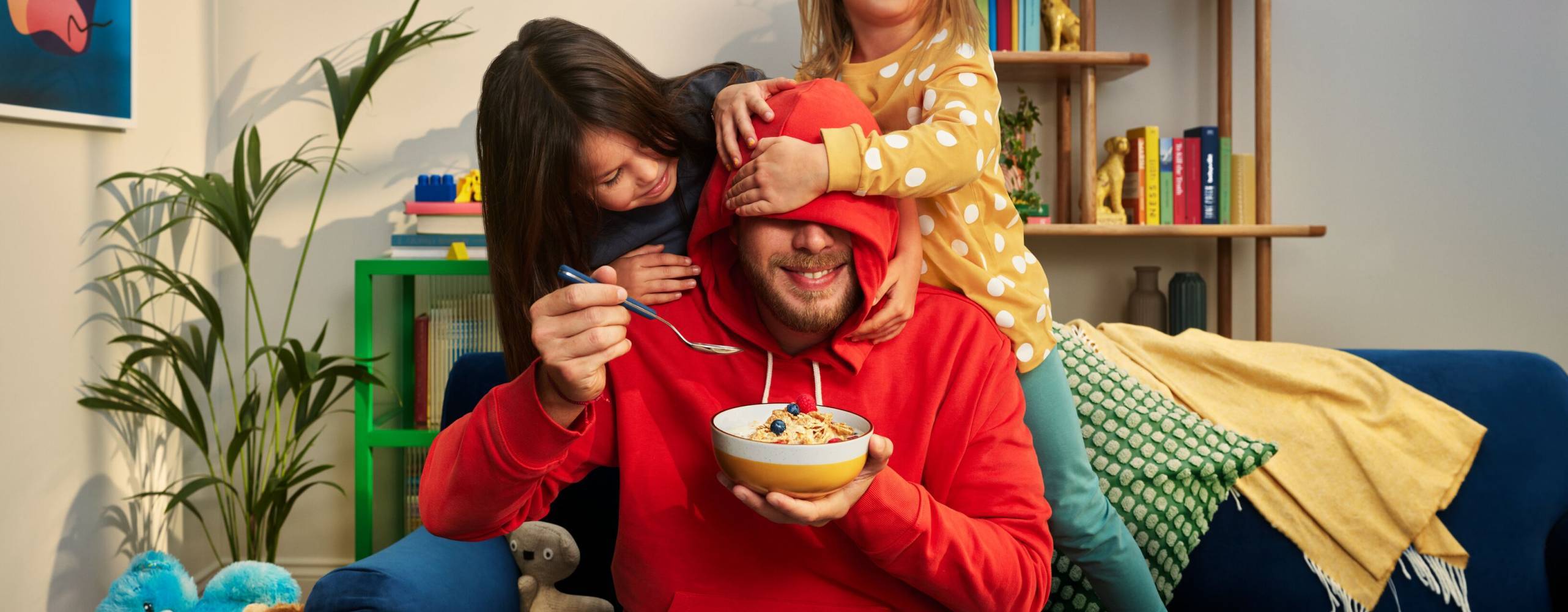 En man, en kvinna och ett barn som äter gröt i en soffa